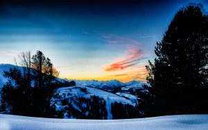 Vue panoramique sur les chalets et les remontées mécaniques de la Plagne, éclairés par le coucher de soleil sur les montagnes en arrière-plan